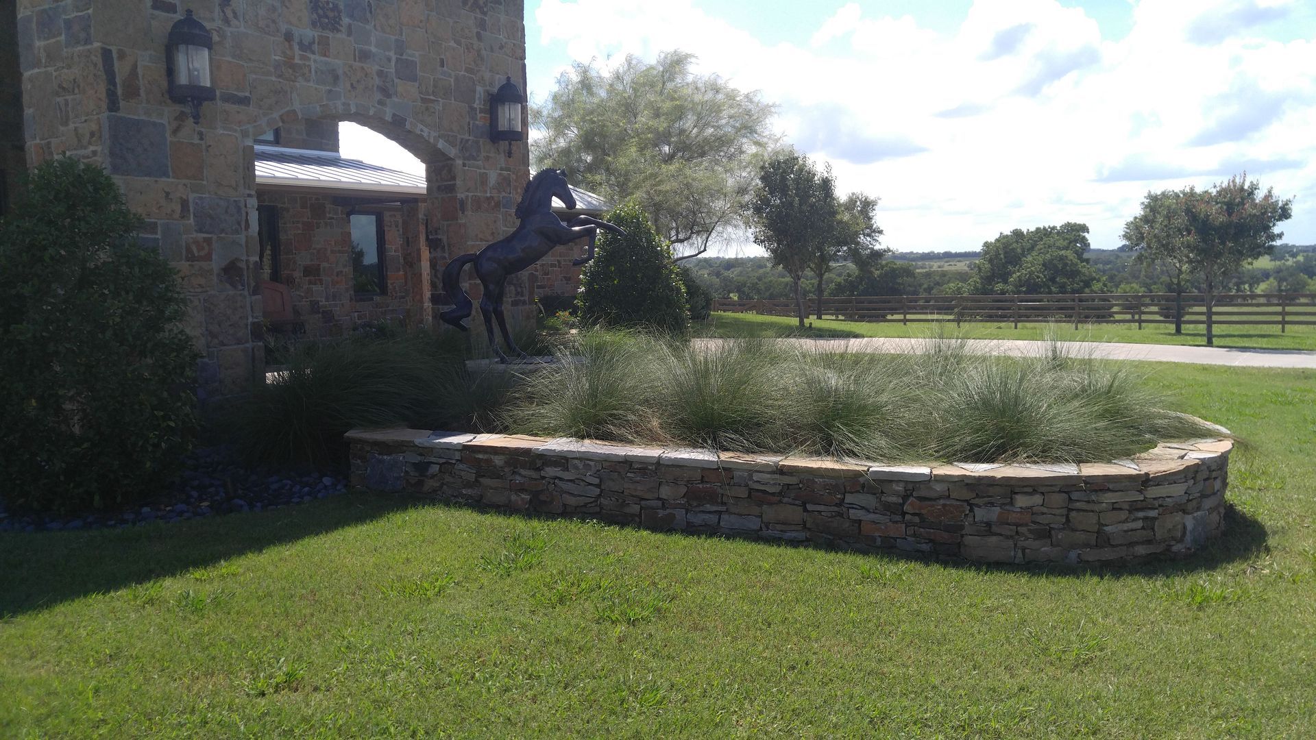 A stone wall with a statue of a horse in front of a stone building.