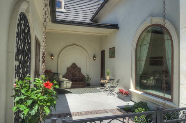 A patio with a table and chairs and flowers in front of a house.