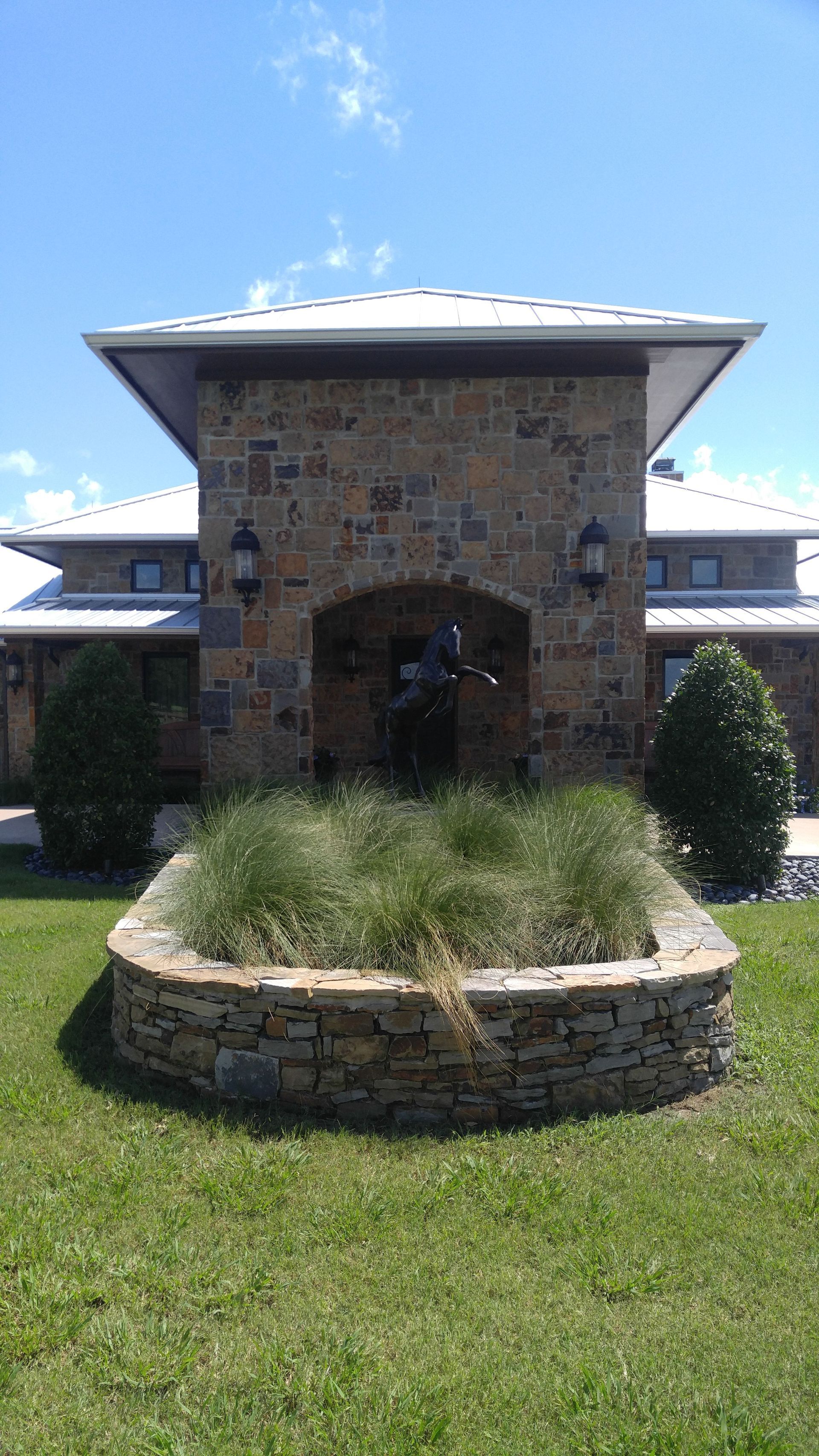 A large stone building with a circular planter in front of it.