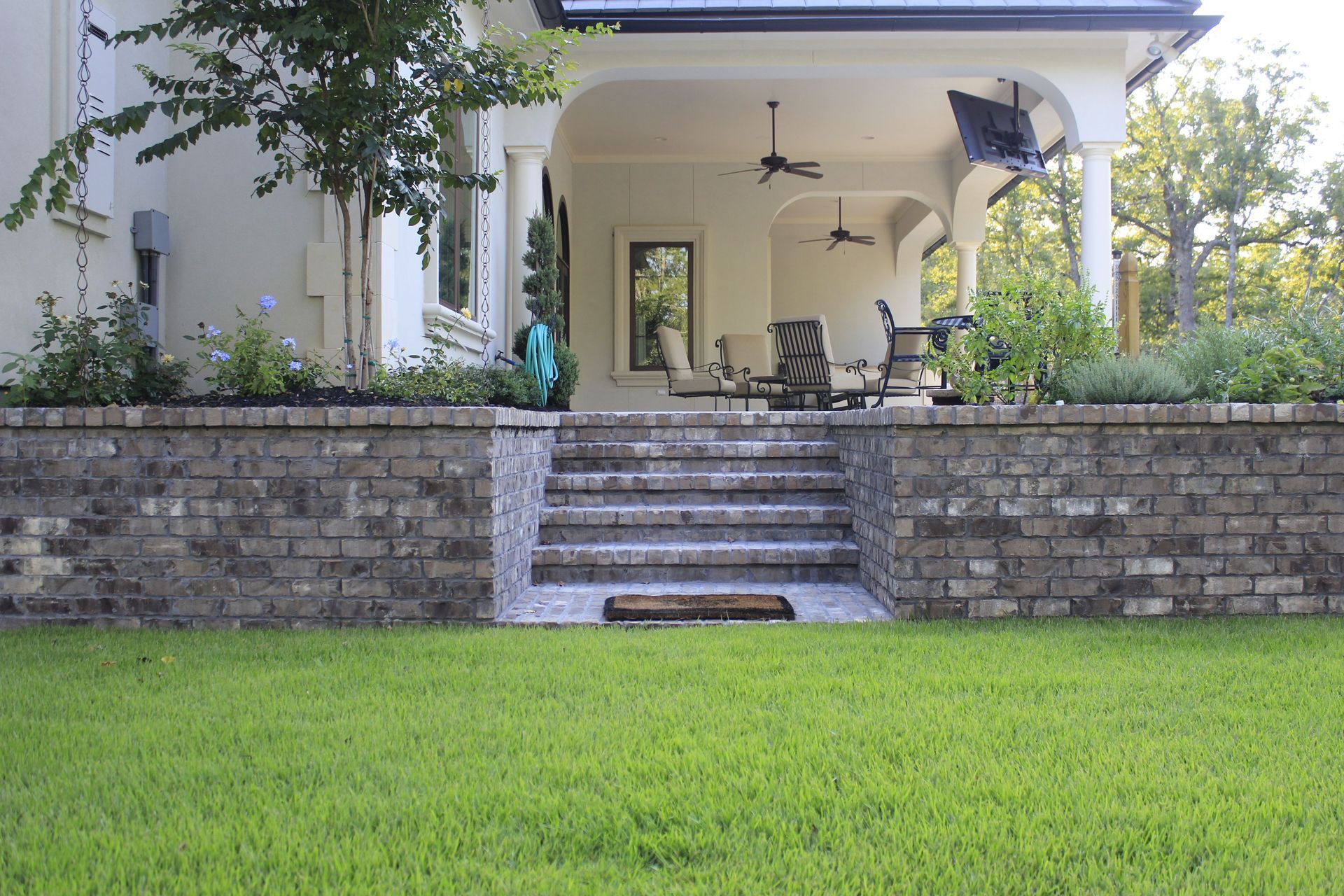 A house with a brick wall and steps leading to a porch.