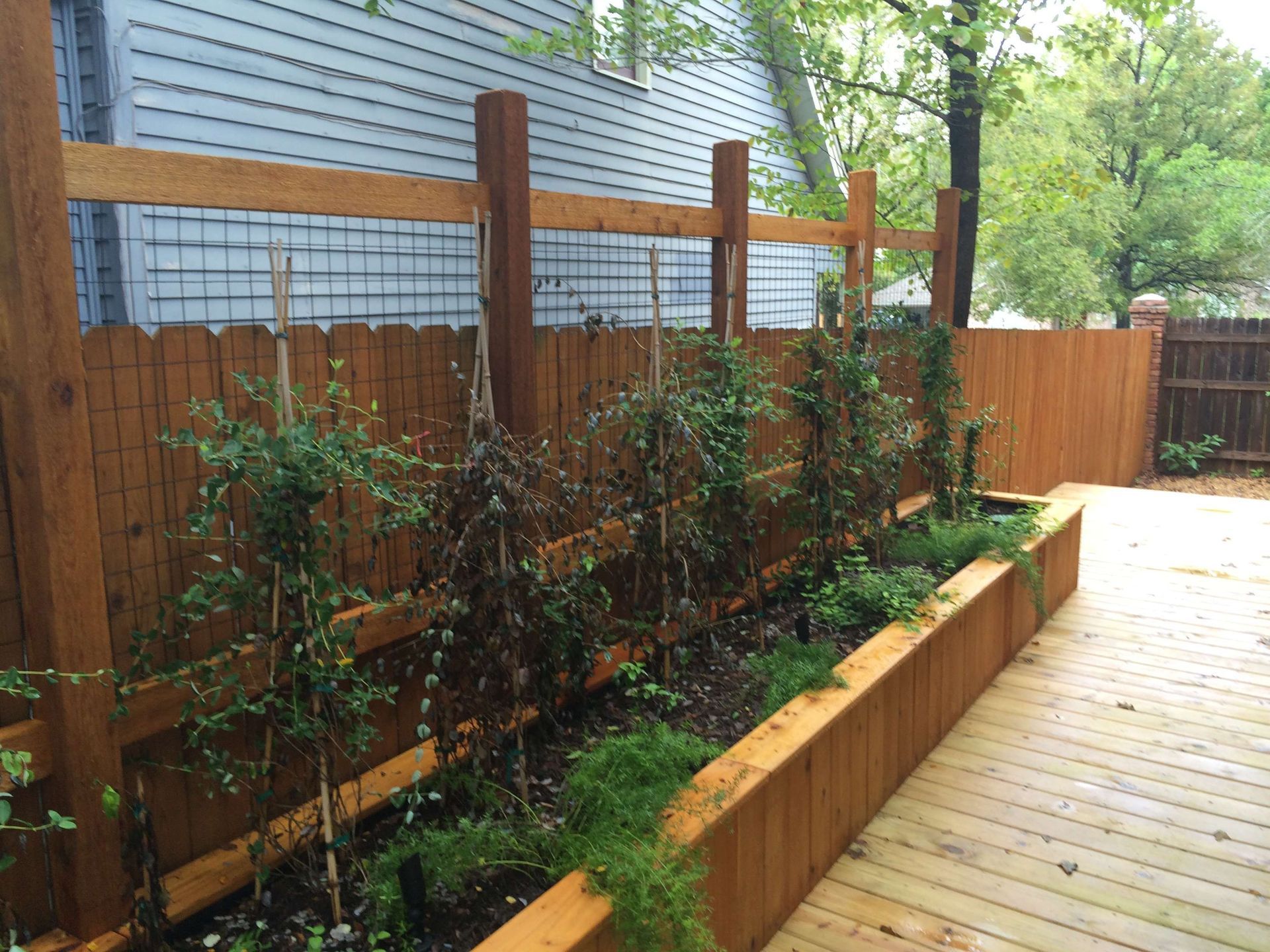 A wooden fence with a garden in front of it.