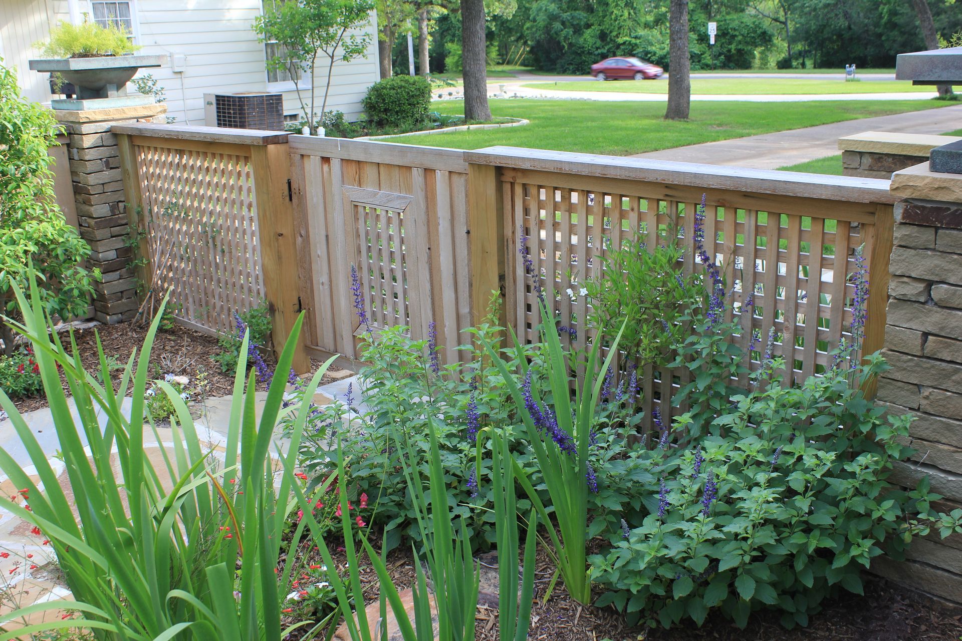 A wooden fence is surrounded by plants in a garden