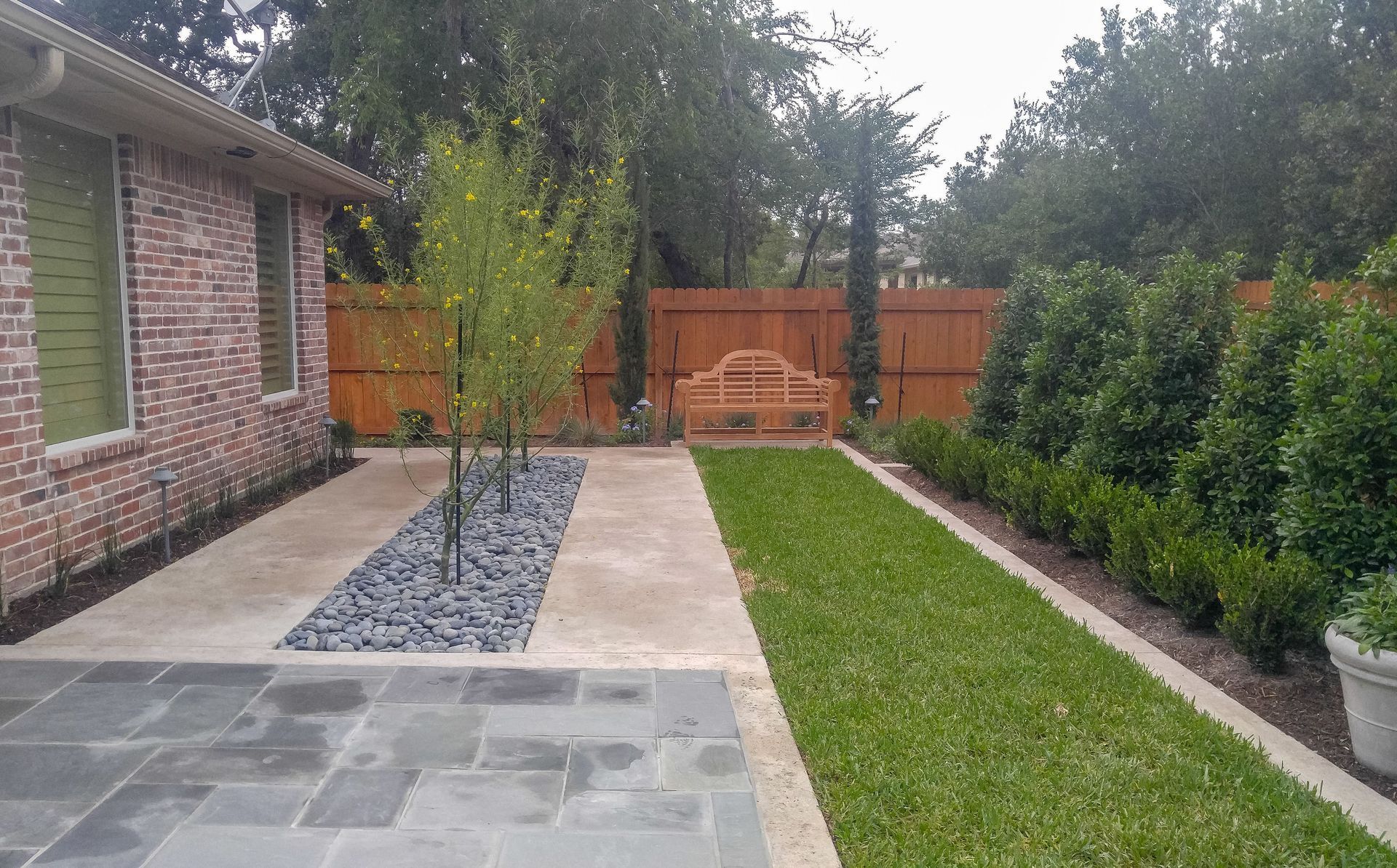 A brick house with a lush green lawn and a wooden fence.