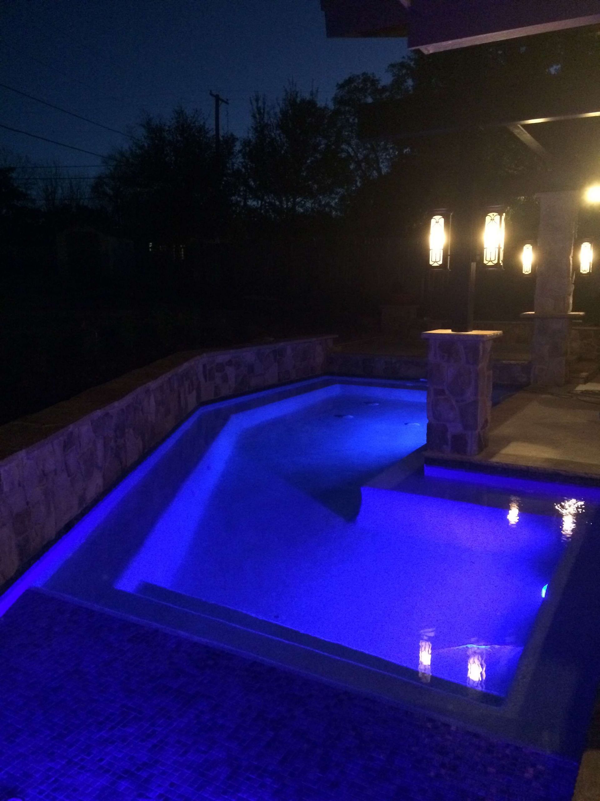 A swimming pool is lit up with blue lights at night