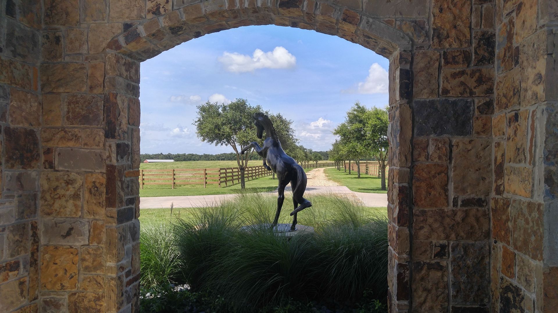 A stone archway with a statue of a horse in the foreground.