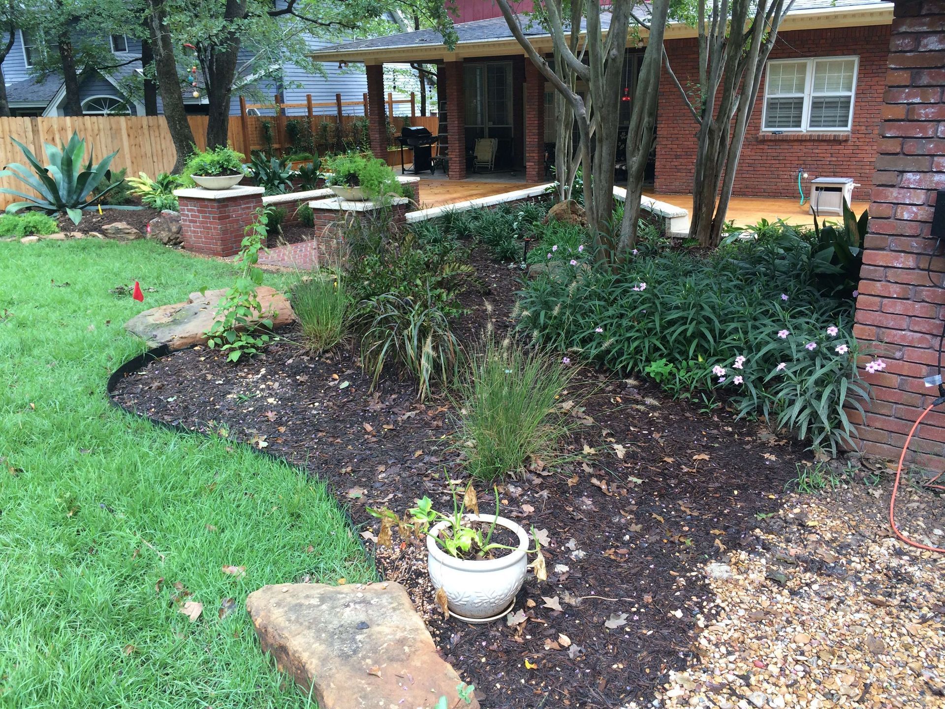 A brick house with a lush green yard and a potted plant in front of it.