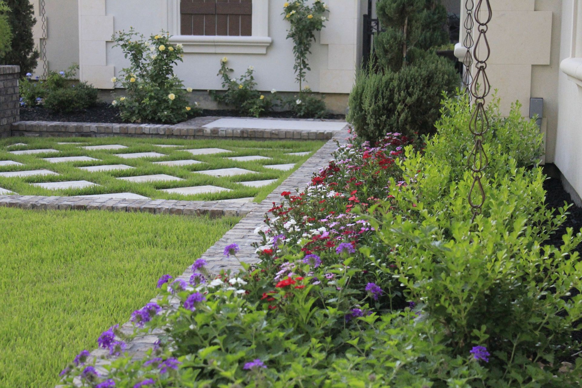 A lawn with flowers and a walkway in front of a house