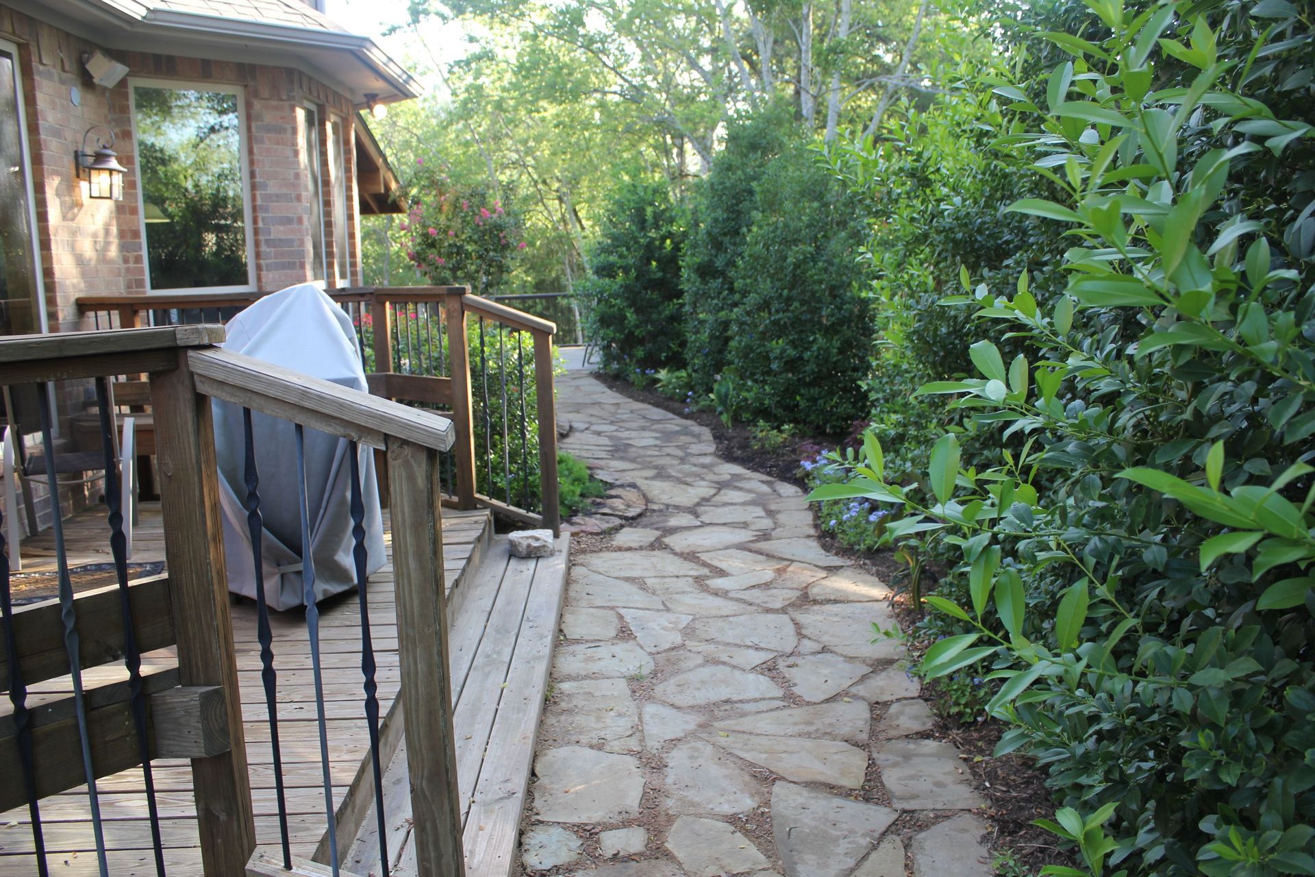 A stone walkway leading to a deck with a grill on it