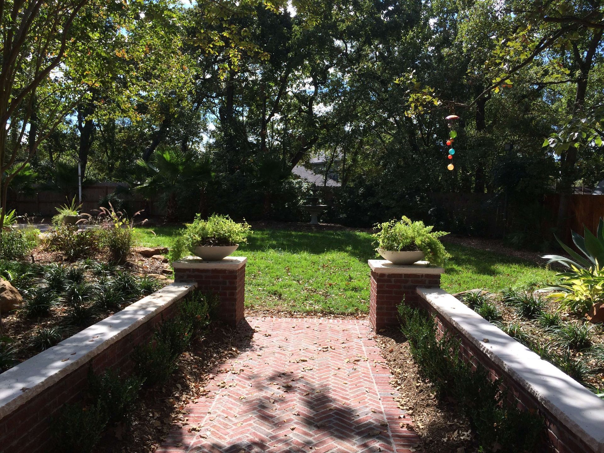 A brick walkway leading to a grassy area with trees in the background