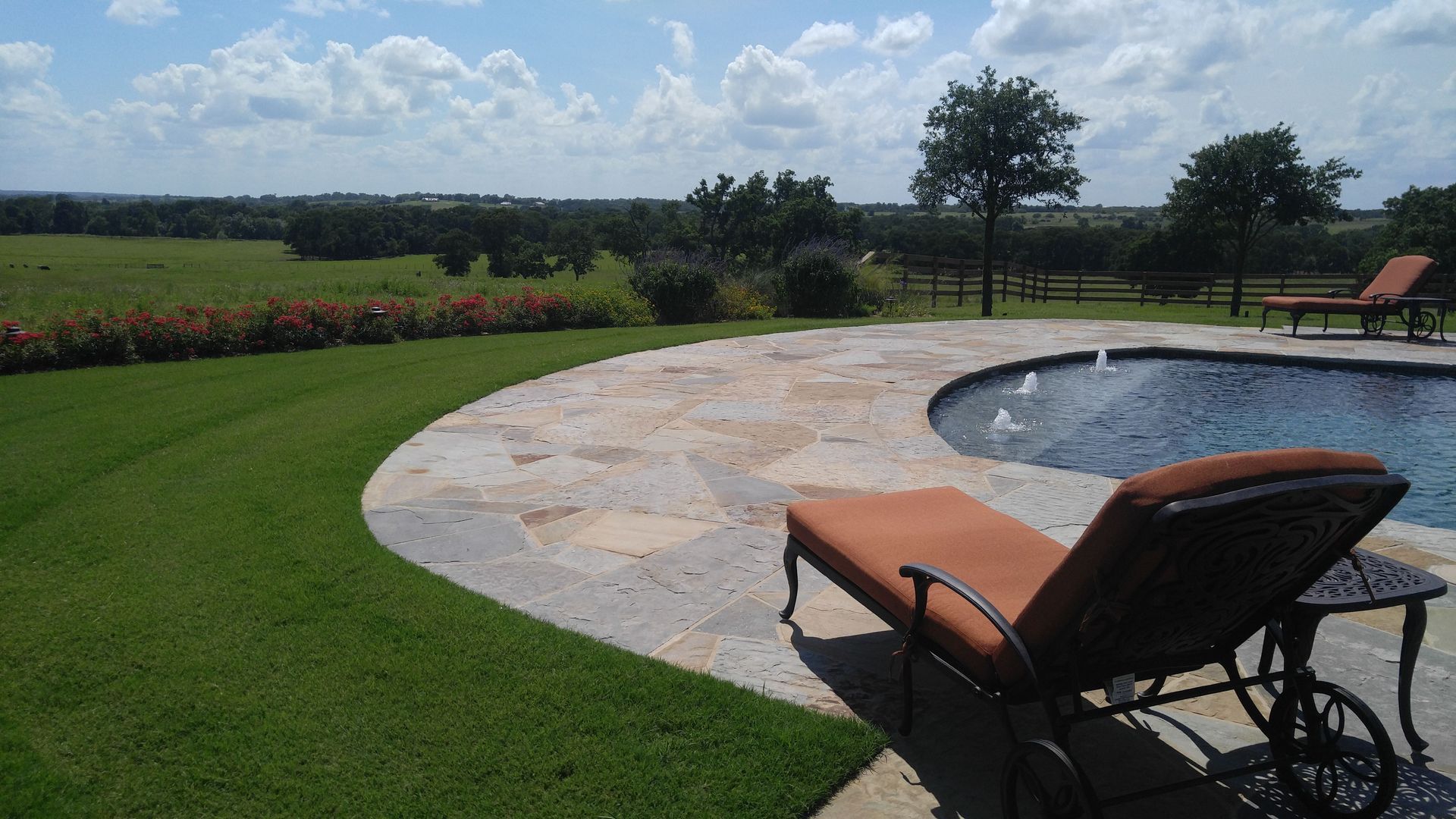 A patio with chairs and a pool in the background