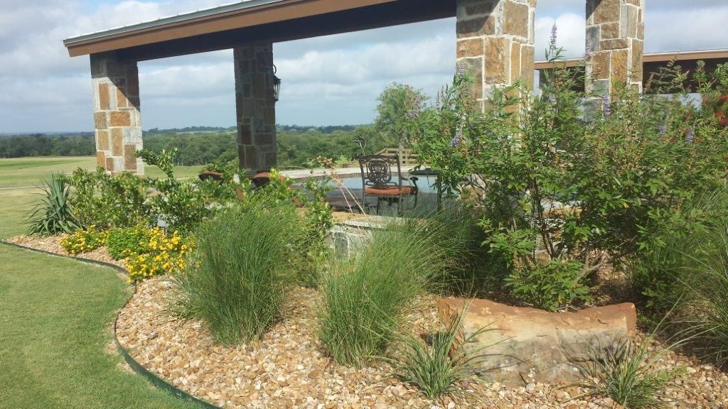 A lush green garden with a stone structure in the background.