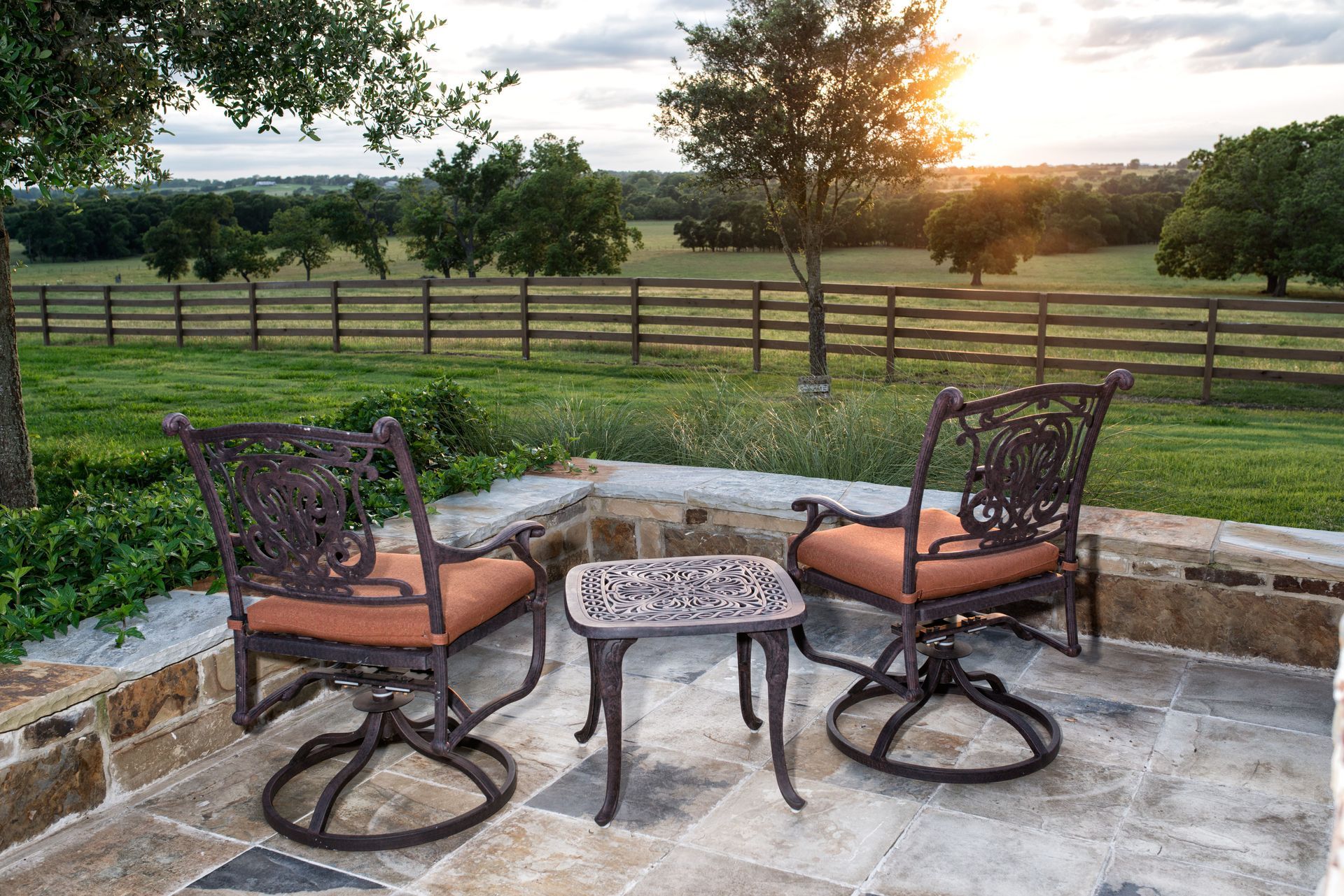 Two chairs and a table on a patio with a fence in the background