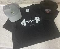 Camiseta deportiva negra con diseño de latidos de barra y dos gorras de béisbol. Una gris y la otra negra.