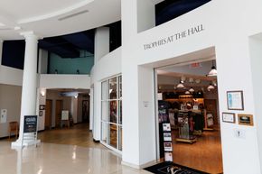 Bright mall hallway with a restaurant entrance, white columns, curved walls, and polished floors