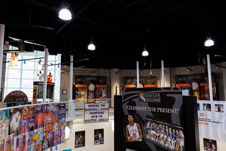 Indoor exhibition booth with colorful posters, hanging lights, and large display banners