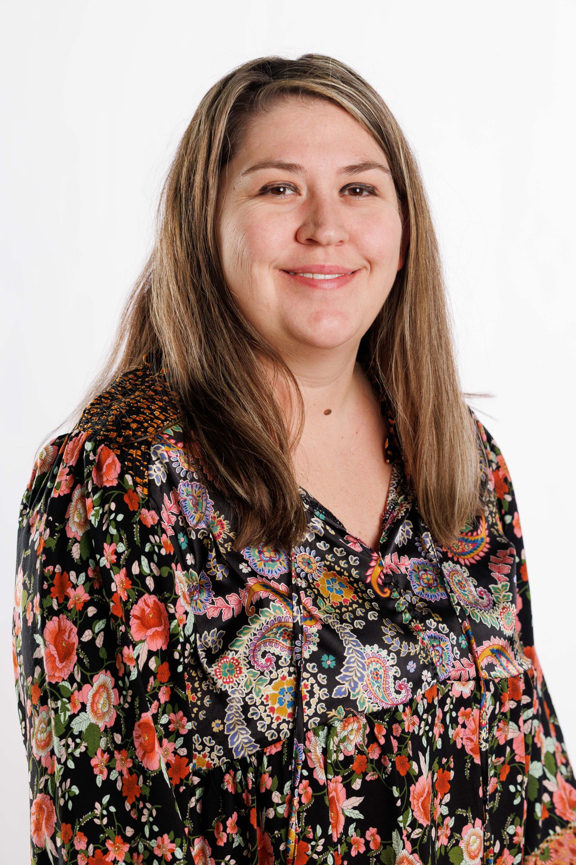 Smiling person in a black floral blouse against a white background