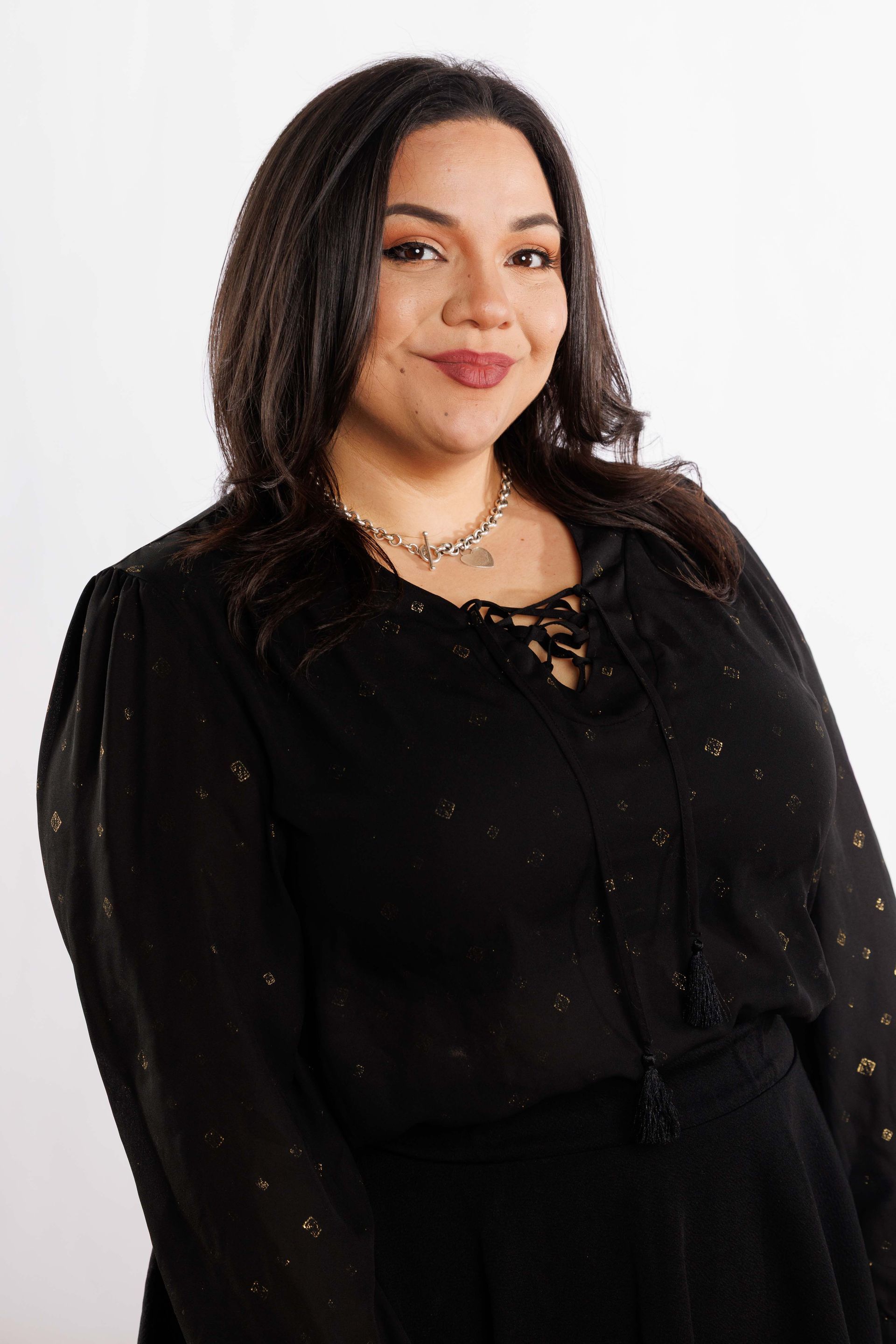 Portrait of a woman in a black outfit, smiling against a white background