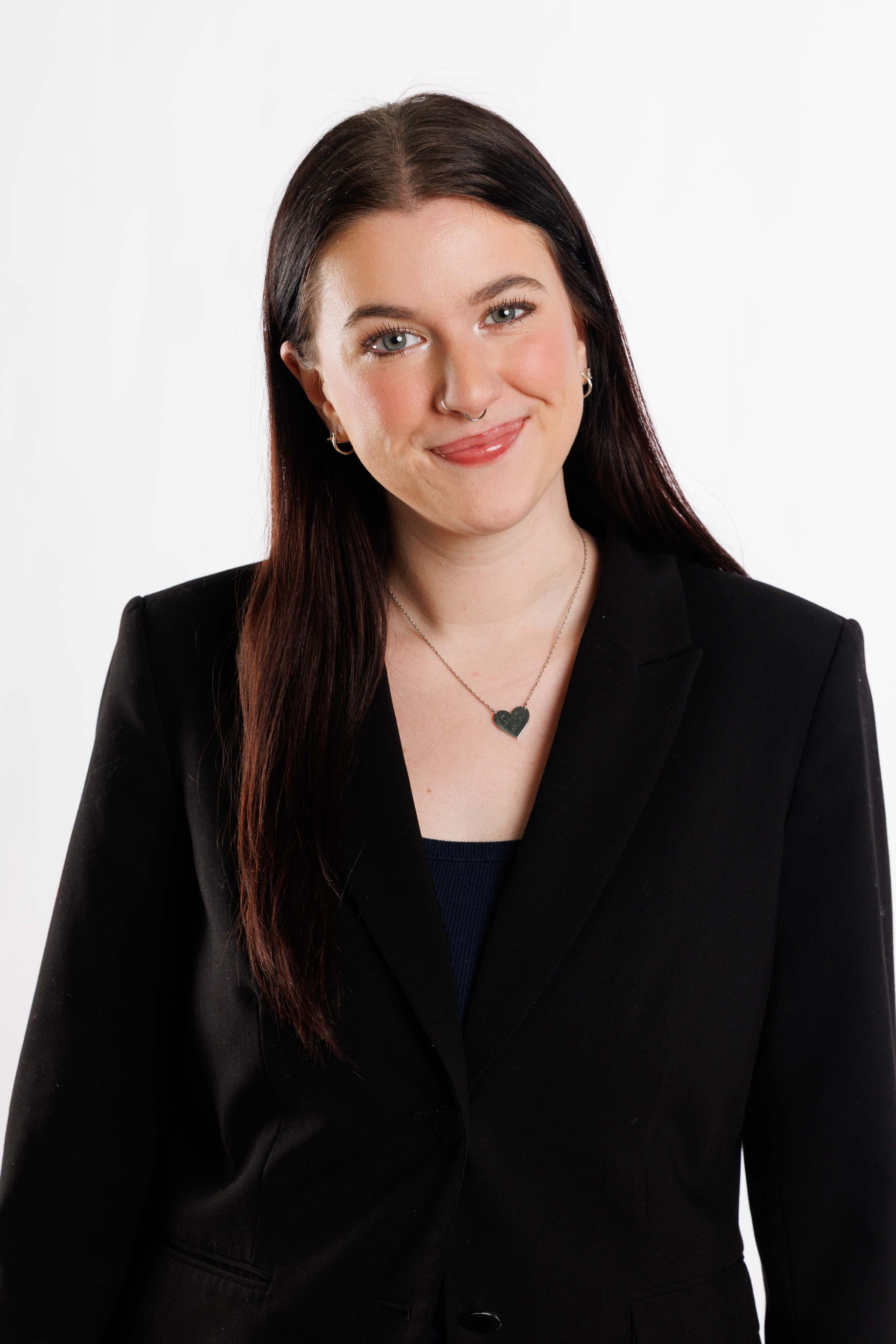 Woman in a black blazer smiling against a white background
