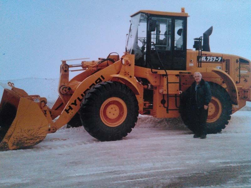 Un homme se tient devant un bulldozer Hyundai jaune