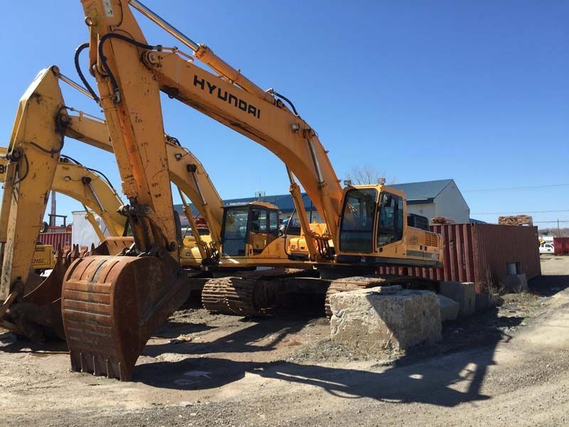 Une excavatrice Hyundai est garée dans un terrain sale