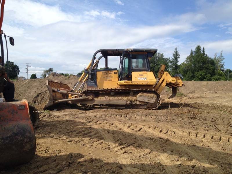 Un bulldozer est assis au milieu d’un champ de terre.
