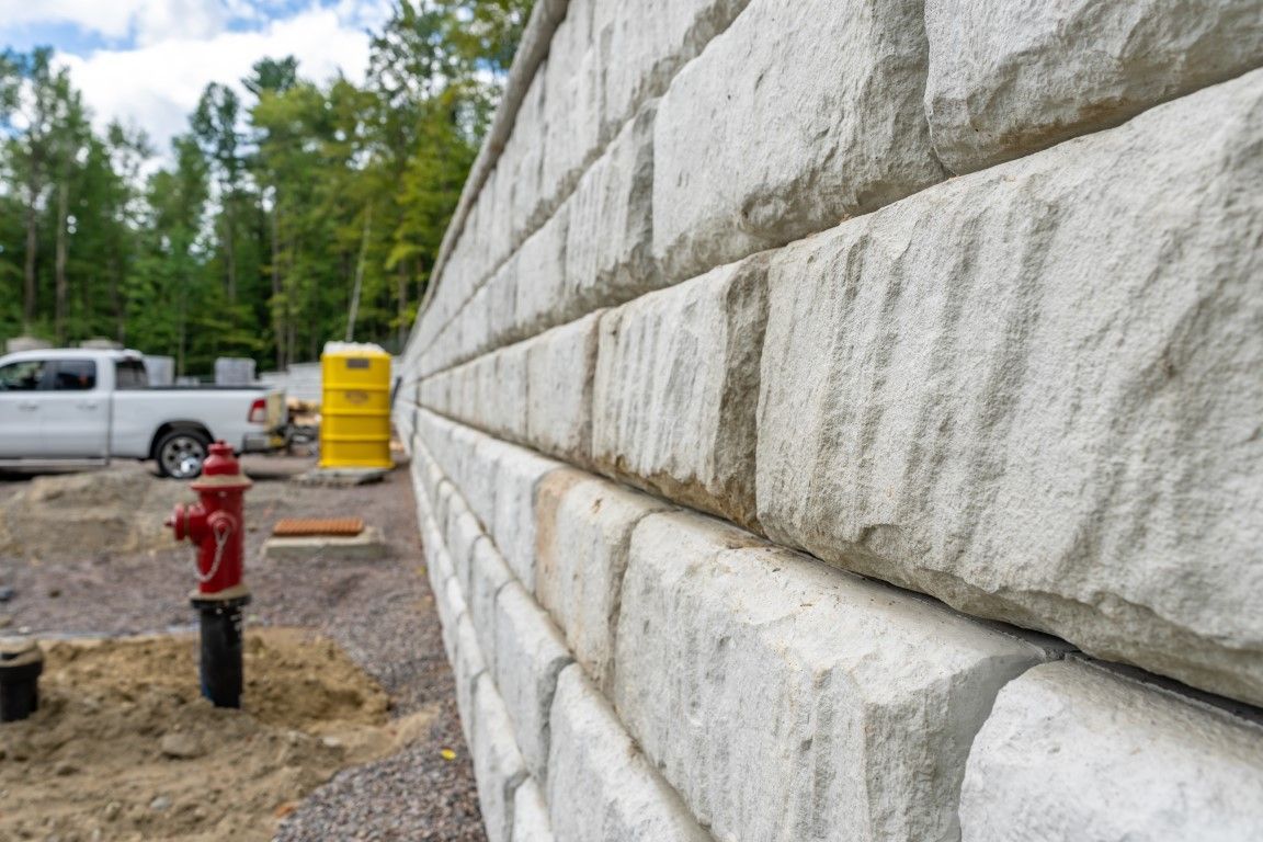 Stone wall with textured blocks; construction site in background.