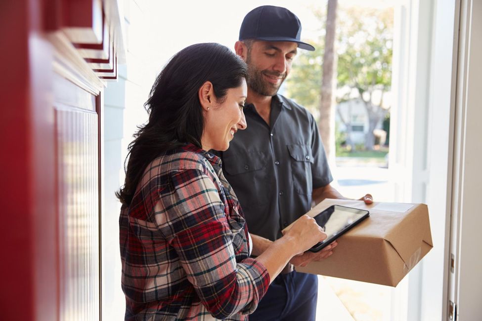 Woman signing for package from delivery person at doorway.