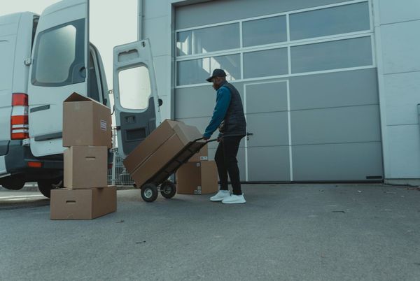 Movers load boxes into a truck as customers review paperwork outside.