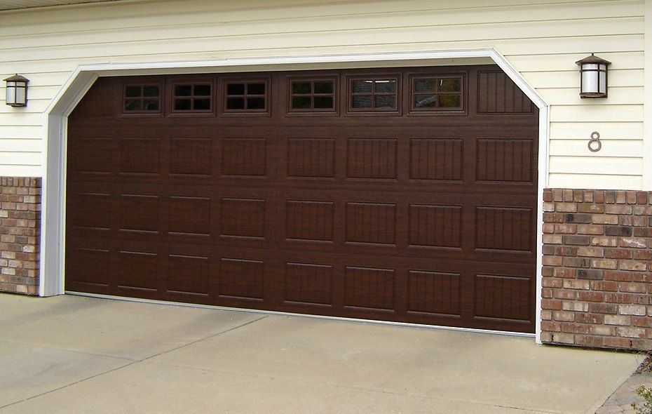A brown garage door is open in front of a house
