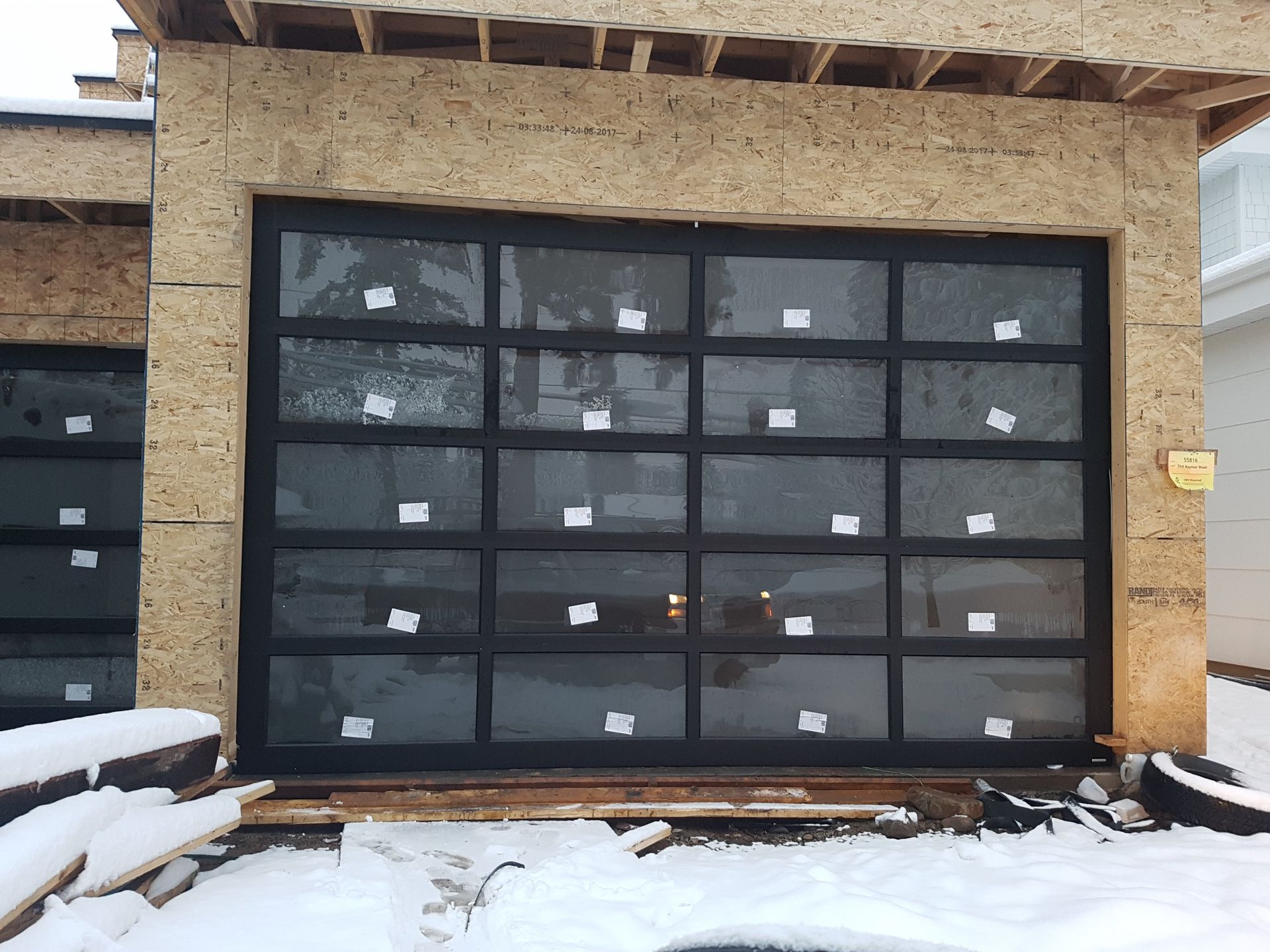 A garage door is being installed in a house under construction.