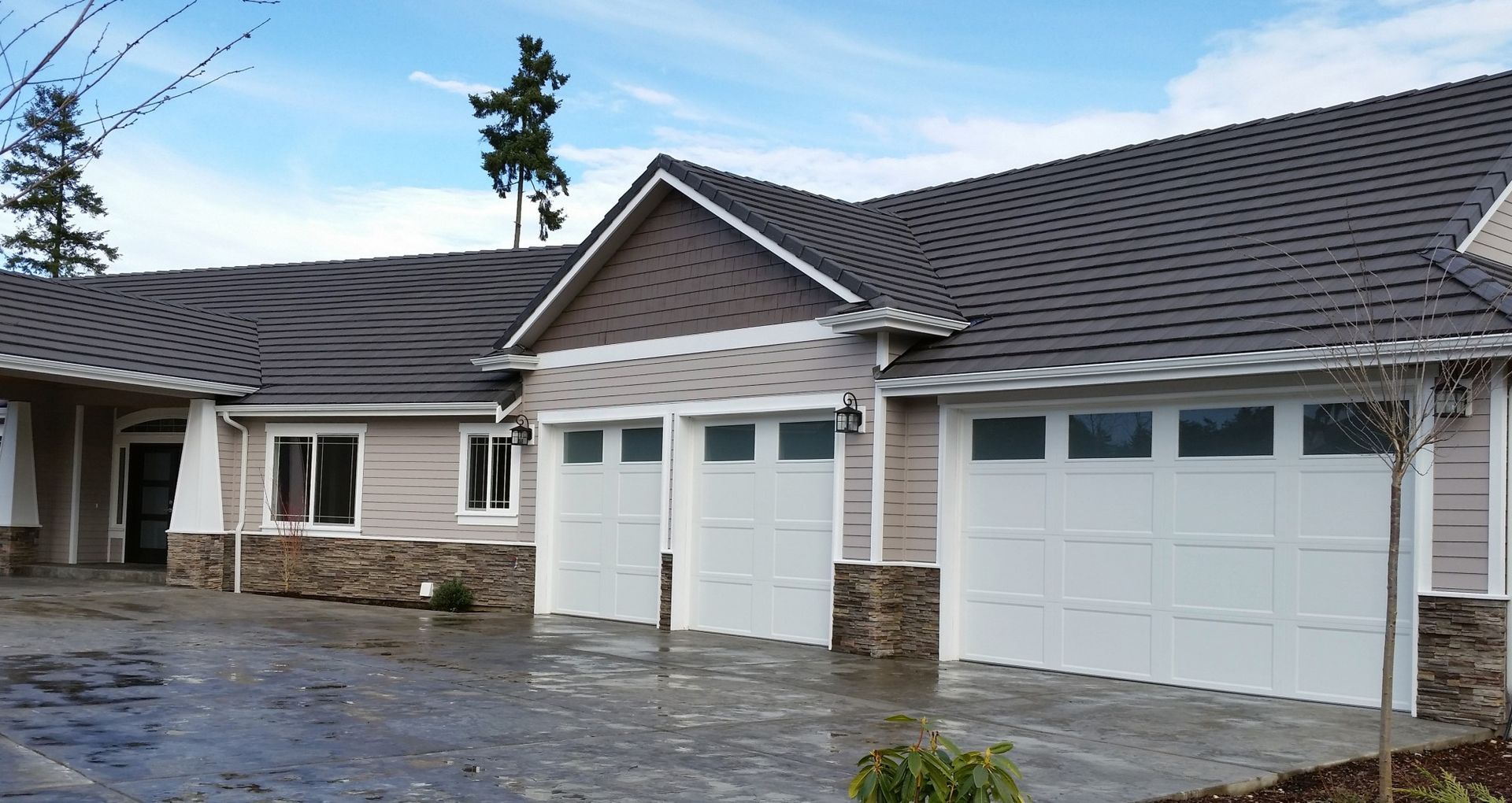 A large house with three garage doors and a gray roof