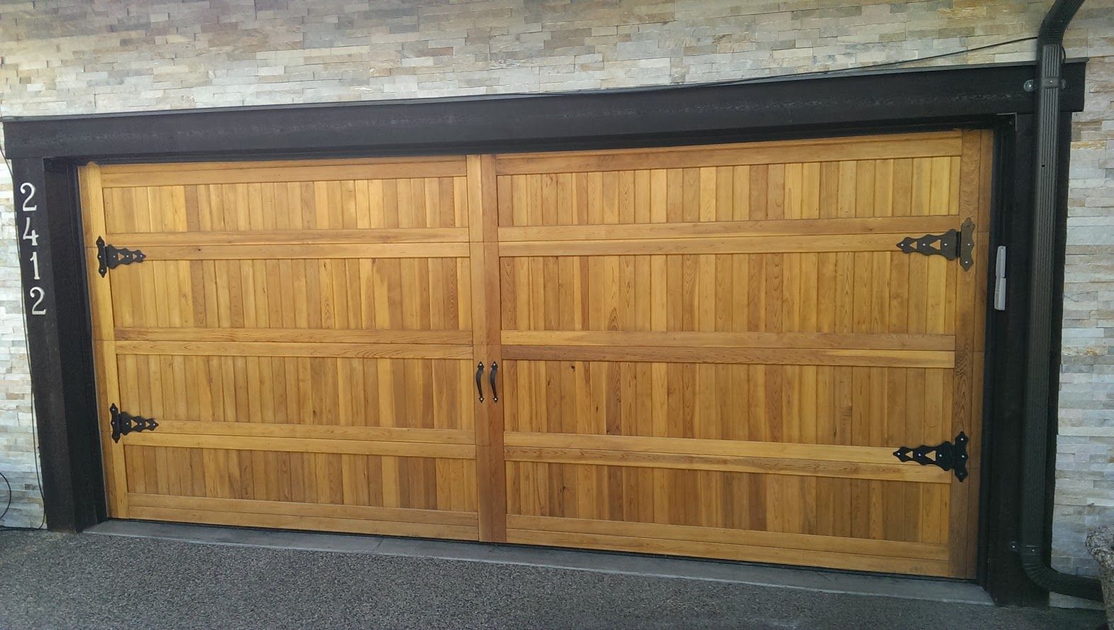 A wooden garage door is sitting on the side of a brick building.