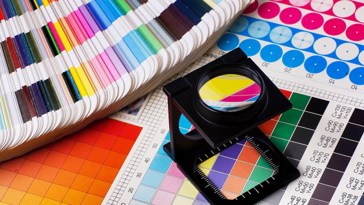 A magnifying glass is sitting on top of a palette of colors.
