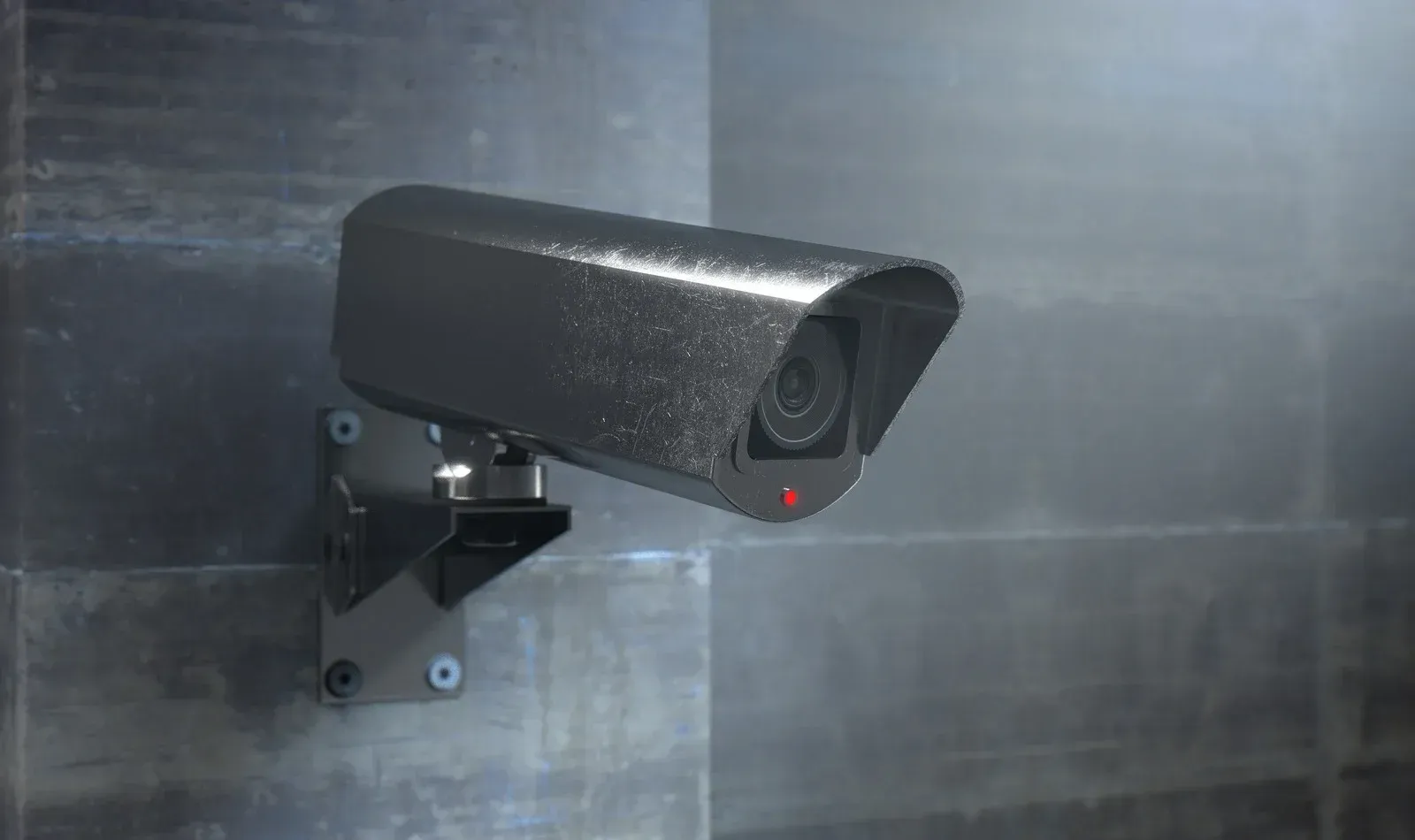 A security camera is mounted on a wall in a dark room.