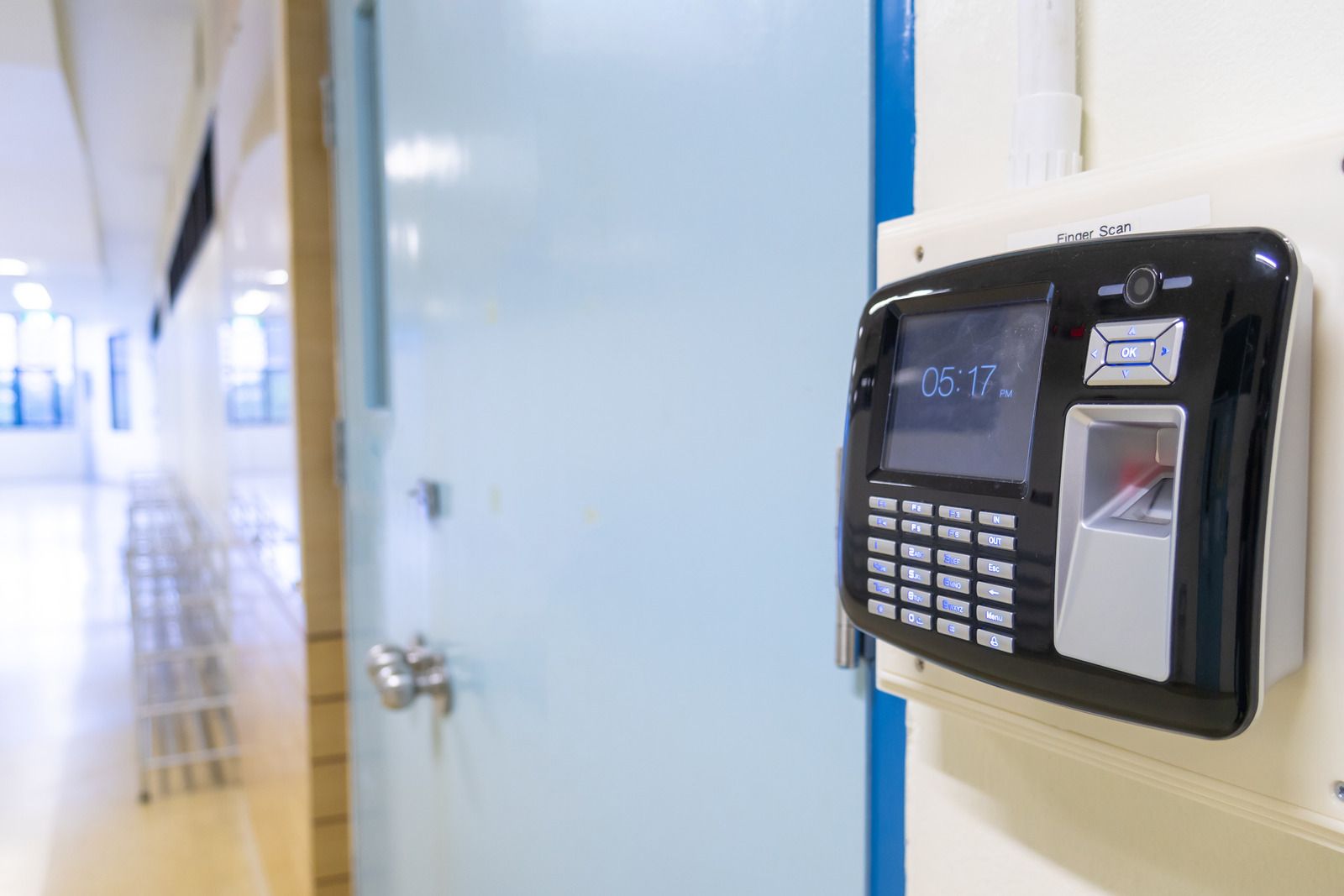 A fingerprint scanner is hanging on a wall next to a door.