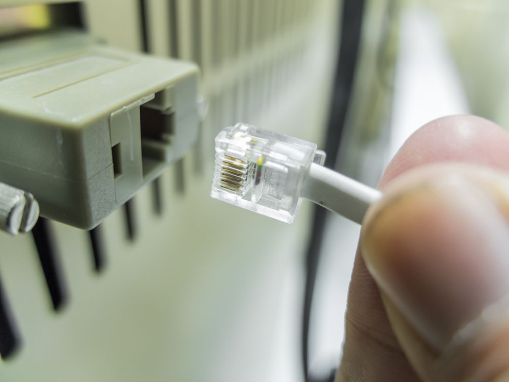 Hand on Connecting Network Cables to Switches — Telecommunications in Caloundra, QLD