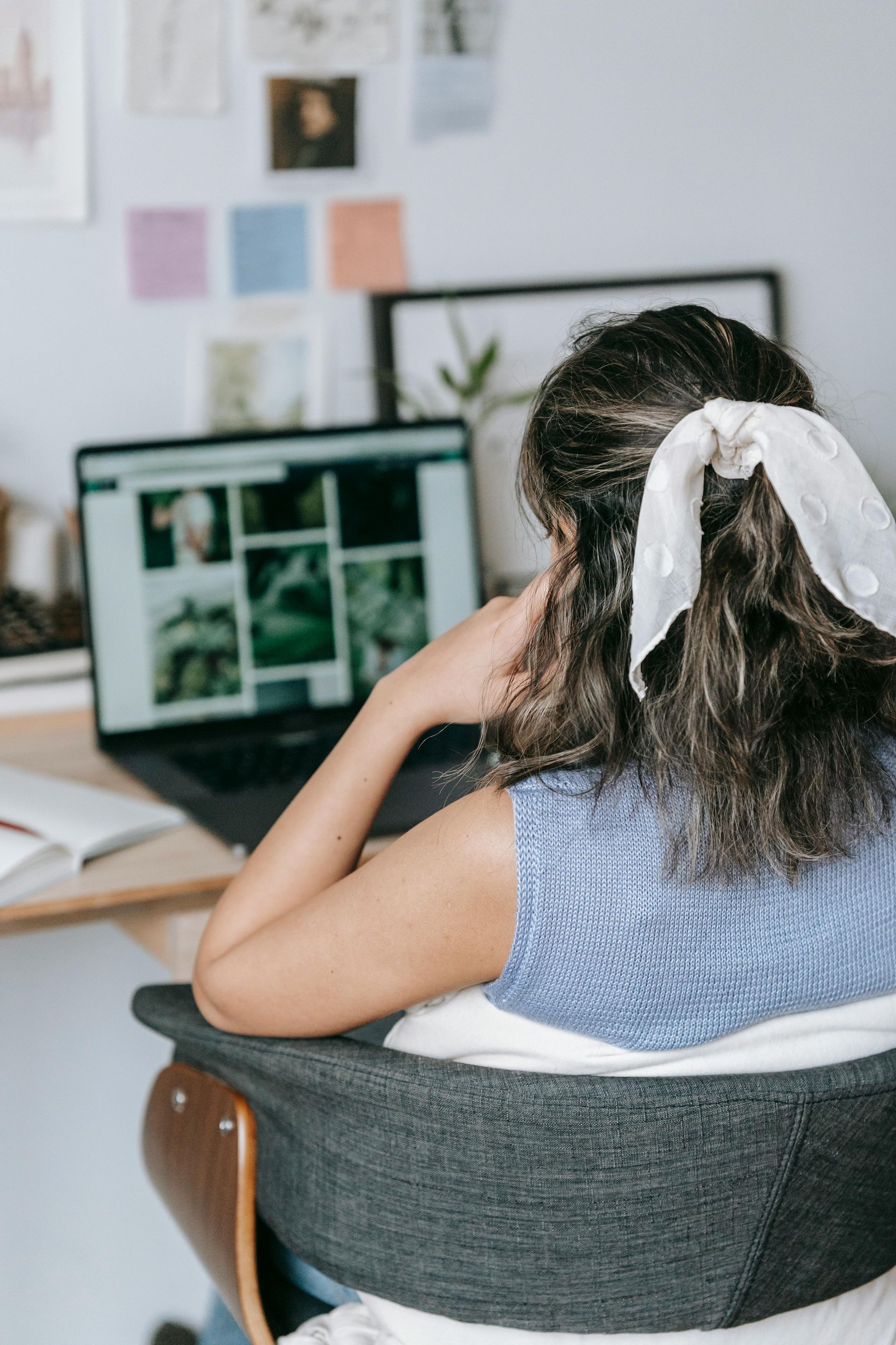 A woman is sitting in a chair in front of a laptop computer.