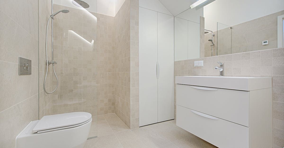 A bathroom with a toilet , sink , shower and mirror.