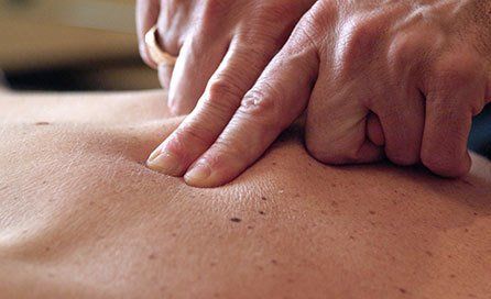 Therapist's fingers digging into a pressure point on a back