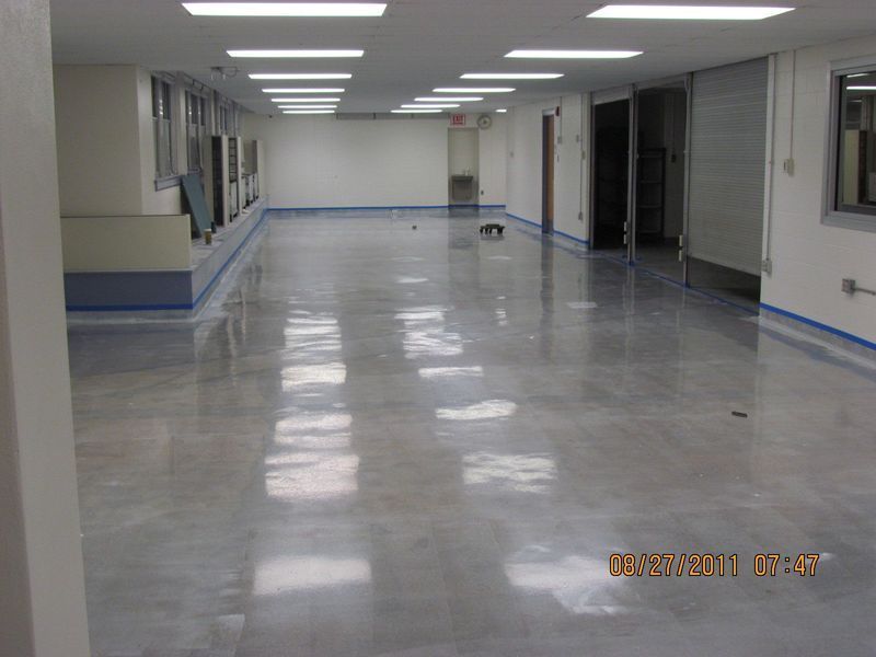 Polished concrete floor in a hallway with recessed lights and closed doors.