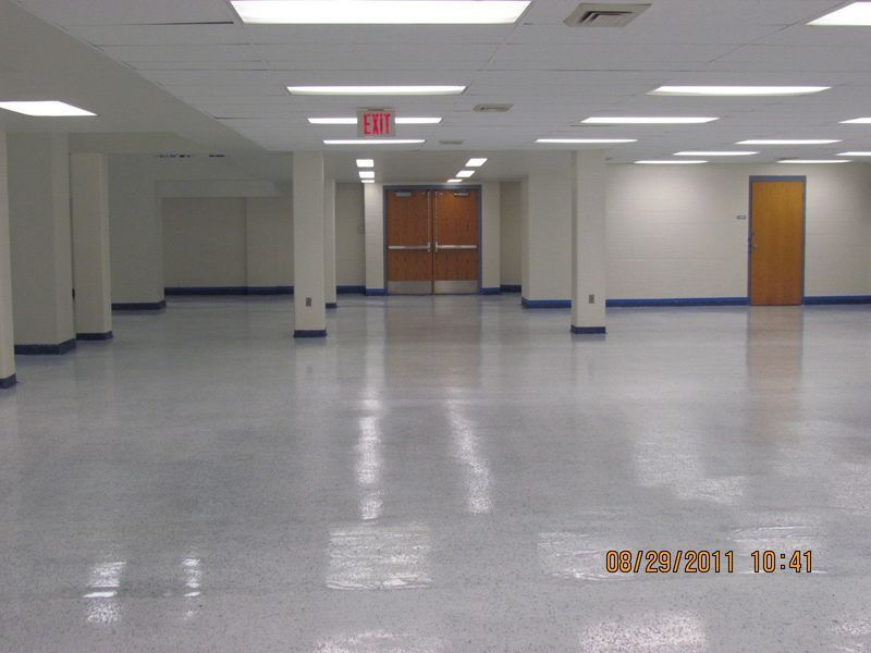 Empty, brightly lit room with a polished floor, white walls, and multiple supporting pillars.