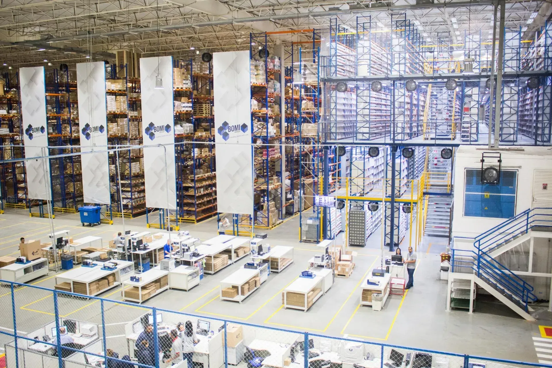 Large warehouse interior with multiple workstations below tall shelving units.