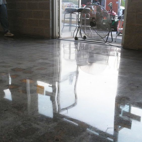 Polished concrete floor reflecting a bright doorway with a fan inside.