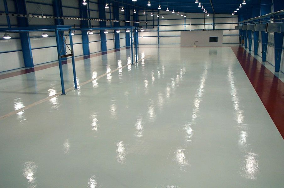 Empty industrial warehouse with a shiny, light-colored floor and red and blue accents.