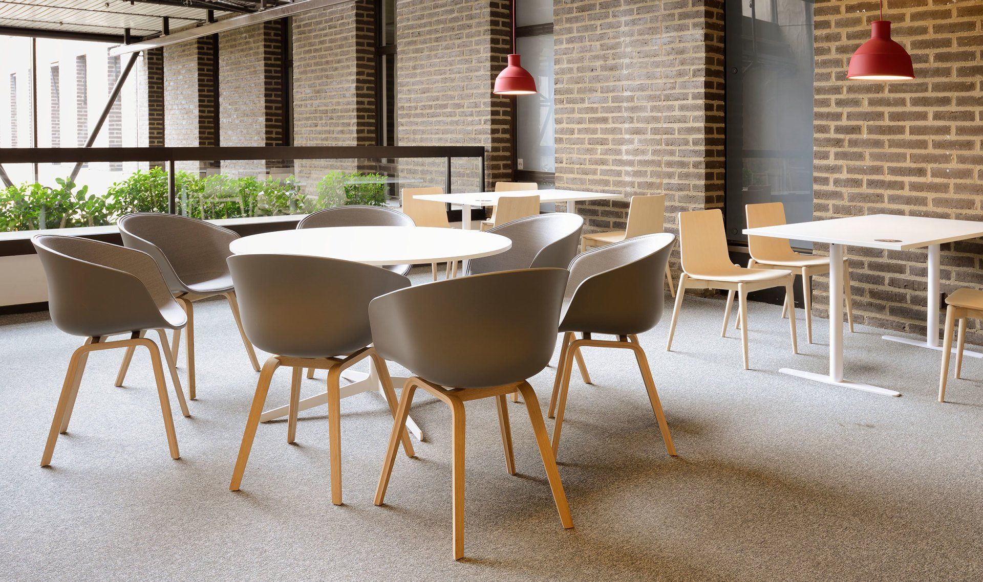Indoor cafe area with round tables, chairs, brick walls, and red pendant lights.