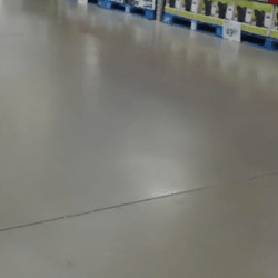 Smooth, gray concrete floor in a store, with distant shelves and blue pallets.