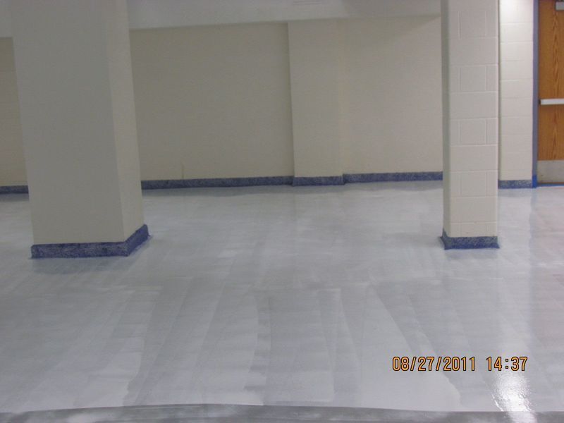 White-painted basement with columns, baseboards, and reflective flooring.