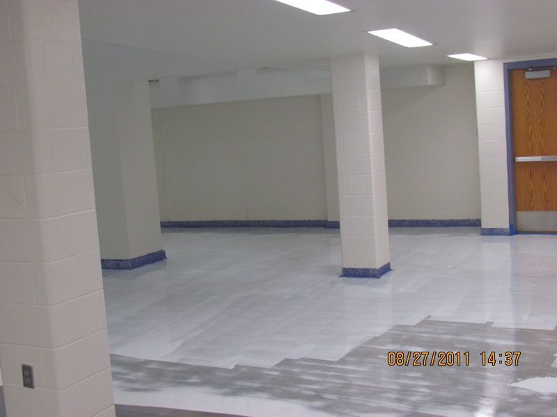 Empty room with white pillars and floor, blue trim, and a closed wooden door.