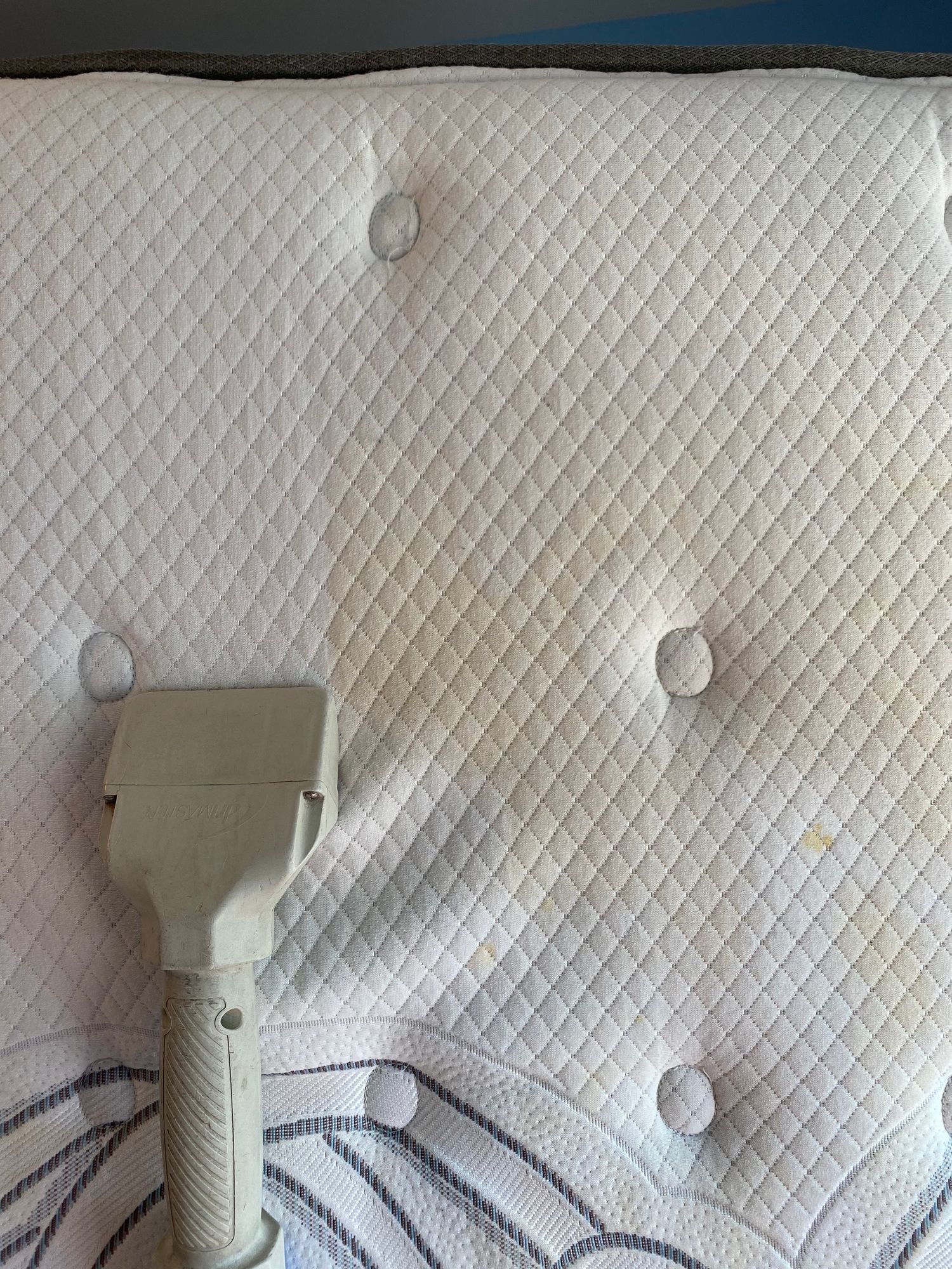 A vacuum cleaner is sitting on top of a white mattress.