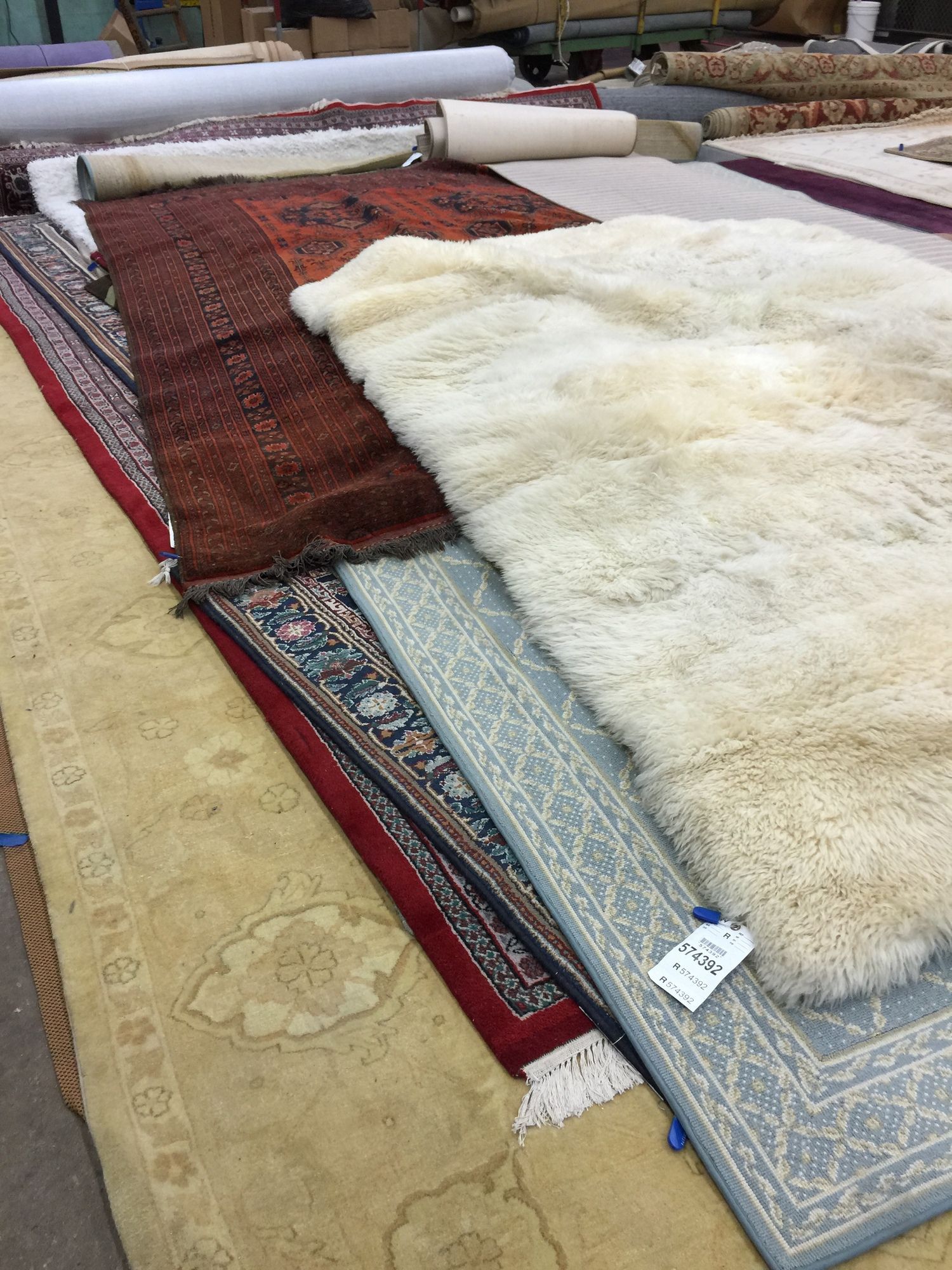 A bunch of rugs are stacked on top of each other in a room.